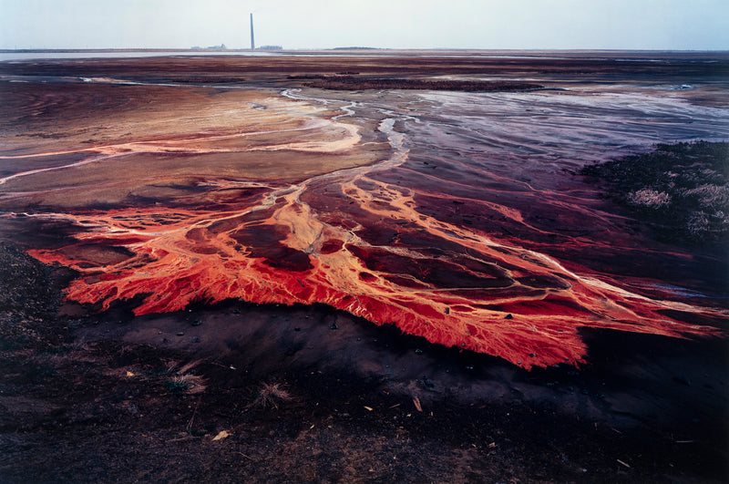 Famous Canadian landscape photographer Edward Burtynsky captures nickel tailings in Sudbury, Ontario in 1996. This photograph depicts a menacing body of molten-orange liquid that sprawls and meanders through a dreary and barren landscape.