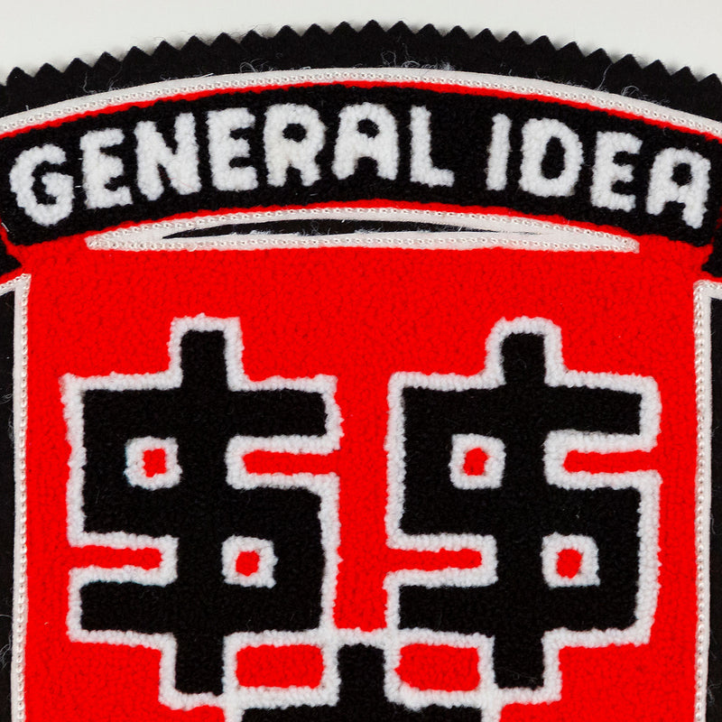 General Idea "Lucre" Chenille Crest, 1989. Editioned textile art by famous Canadian artist trio, which features three dollar signs set against a florescent red background.