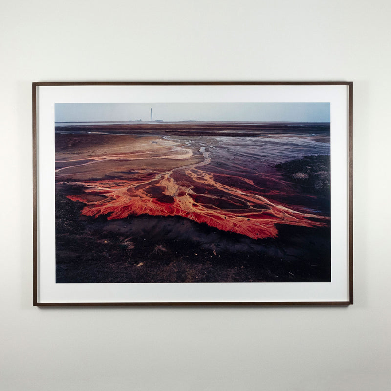 Famous Canadian landscape photographer Edward Burtynsky captures nickel tailings in Sudbury, Ontario in 1996. This photograph depicts a menacing body of molten-orange liquid that sprawls and meanders through a dreary and barren landscape.