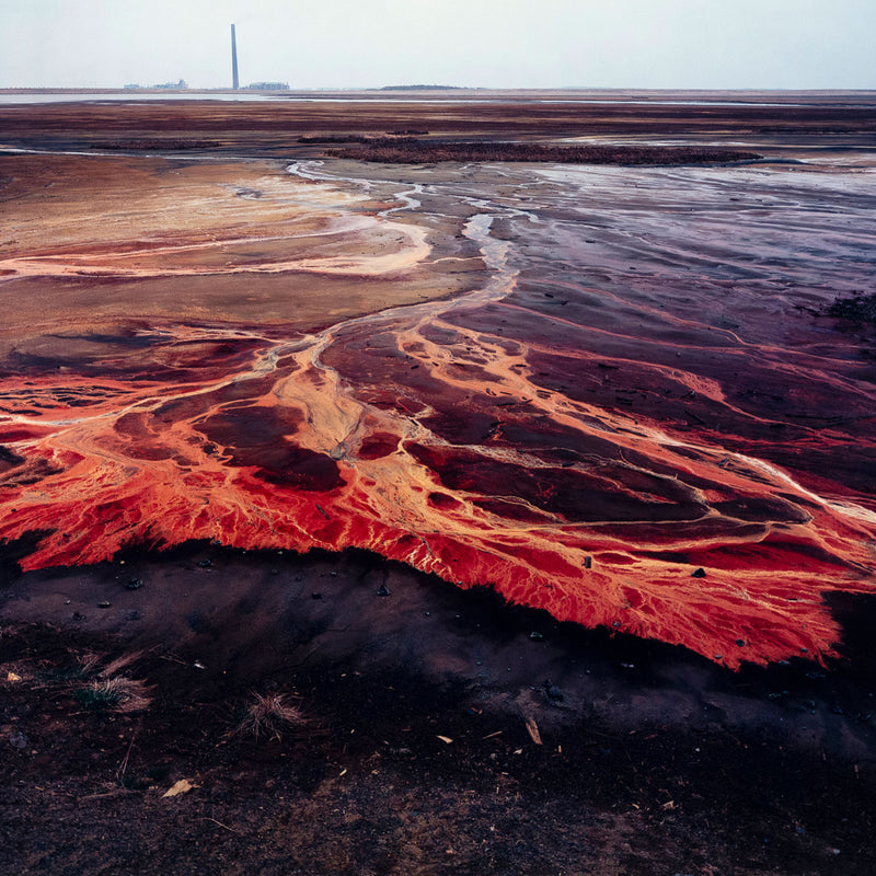 Famous Canadian landscape photographer Edward Burtynsky captures nickel tailings in Sudbury, Ontario in 1996. This photograph depicts a menacing body of molten-orange liquid that sprawls and meanders through a dreary and barren landscape.