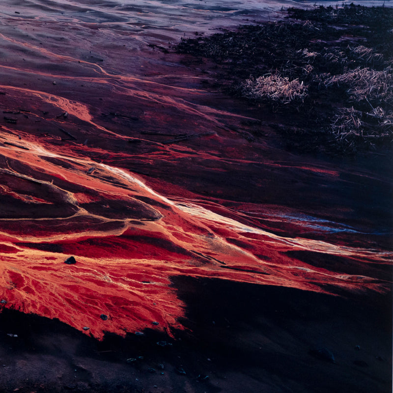 Famous Canadian landscape photographer Edward Burtynsky captures nickel tailings in Sudbury, Ontario in 1996. This photograph depicts a menacing body of molten-orange liquid that sprawls and meanders through a dreary and barren landscape.