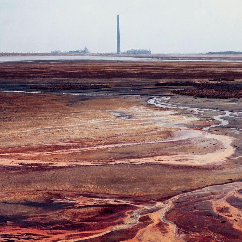 Famous Canadian landscape photographer Edward Burtynsky captures nickel tailings in Sudbury, Ontario in 1996. This photograph depicts a menacing body of molten-orange liquid that sprawls and meanders through a dreary and barren landscape.