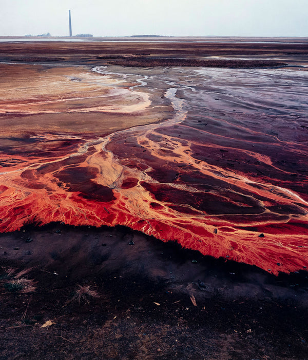 Famous Canadian landscape photographer Edward Burtynsky captures nickel tailings in Sudbury, Ontario in 1996.  This photograph depicts a menacing body of molten-orange liquid that sprawls and meanders through a dreary and barren landscape. 