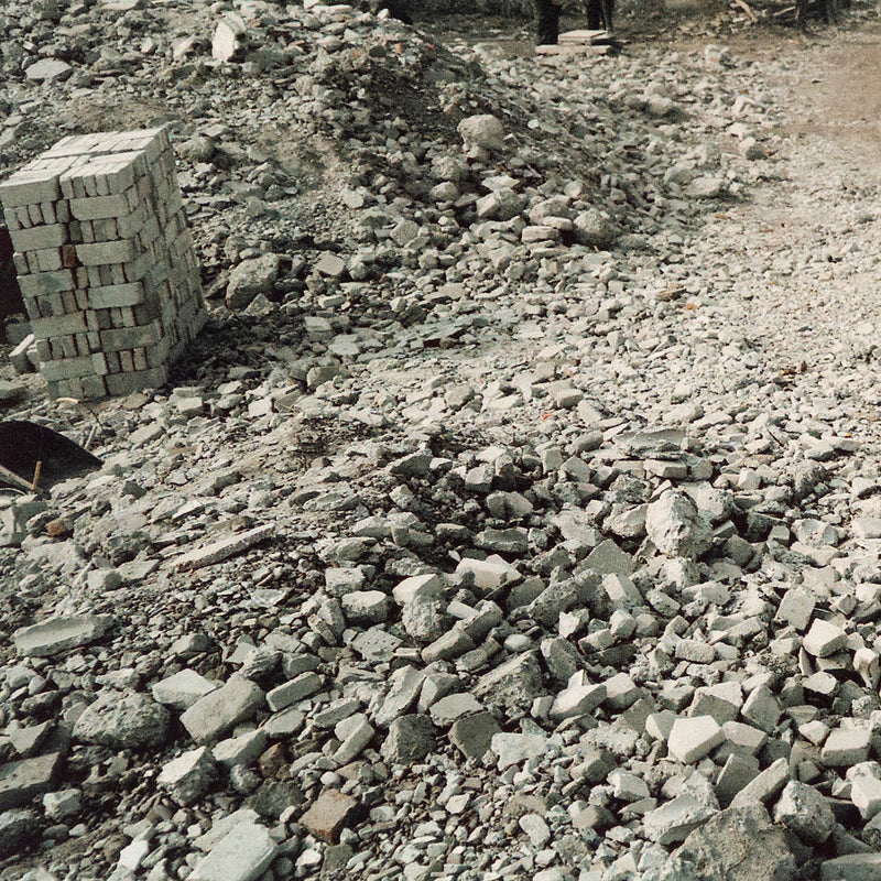 Shot in 2002, Canadian photographer Edward Burtynsky, captures "Feng Jie #5". Depicting a demolished landscape, the photograph is marked by piles of rubble and a dusty haze that obscures the background. Centered in the middle of the work is a man leading his donkey down a dirt road amidst the destruction.