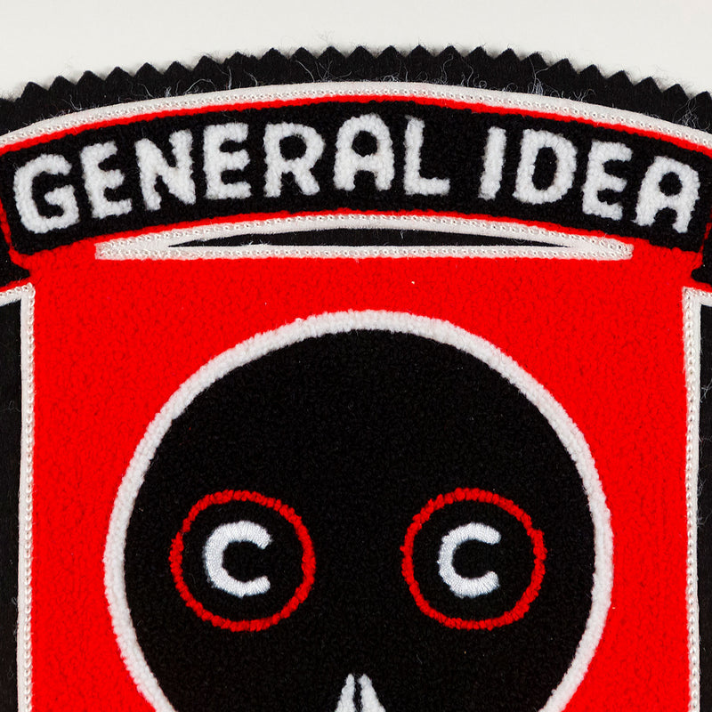 General Idea "Eye of the Beholder" Chenille crest, 1989. Editioned series by Famous Canadian artist trio, which features their iconic skull motif against a florescent red background.