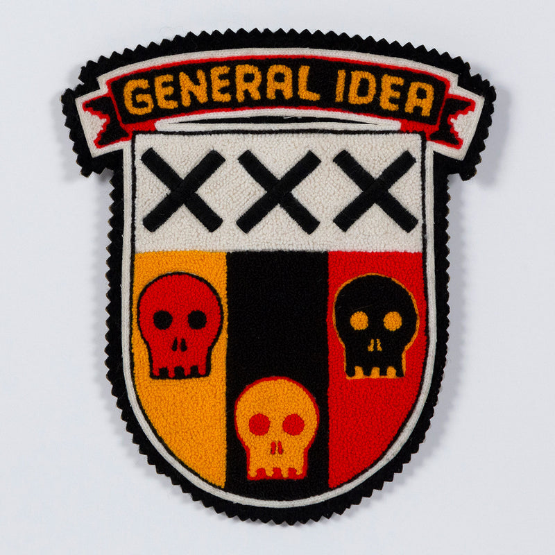 General Idea "Post Mortem" Chenille crest, 1988. Textile patch featurings a trio of skulls and alternating shades of yellow, red, and black.