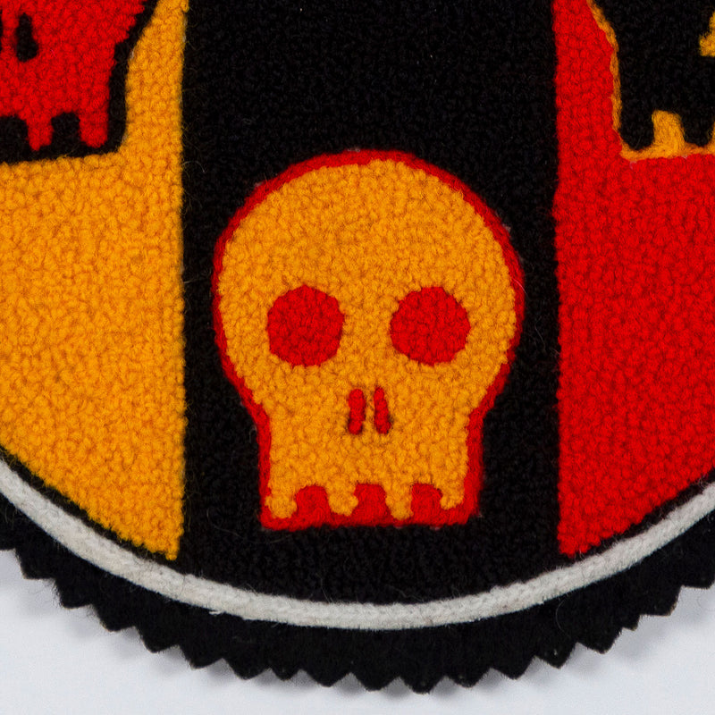 General Idea "Post Mortem" Chenille crest, 1988. Textile patch featurings a trio of skulls and alternating shades of yellow, red, and black.