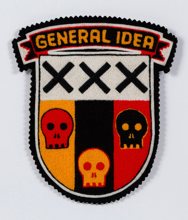 General Idea "Post Mortem" Chenille crest, 1988. Textile patch featurings a trio of skulls and alternating shades of yellow, red, and black.