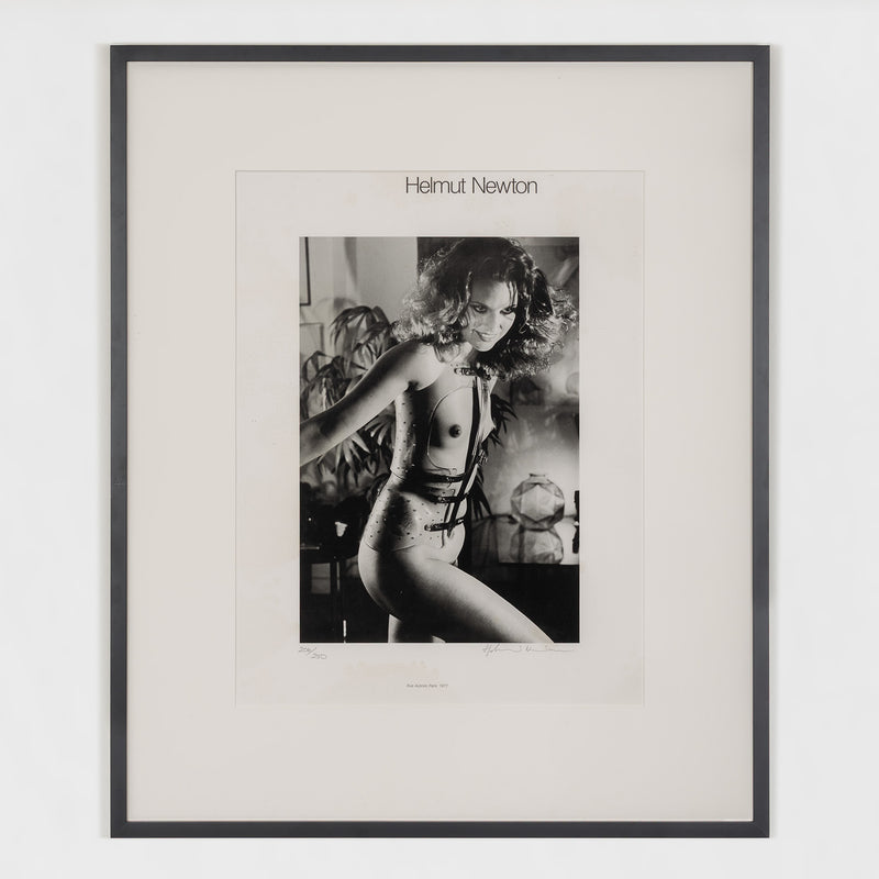 Framed black and white photograph by Helmut Newton featuring a model in a provocative pose.
