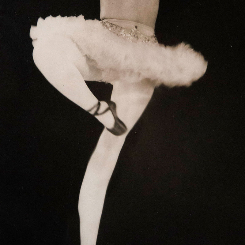 Detail image featuring the work of famous photographer Weegee. A ballerina poses while wearing a tutu and pointe shoes. Vintage black and white photography for sale.