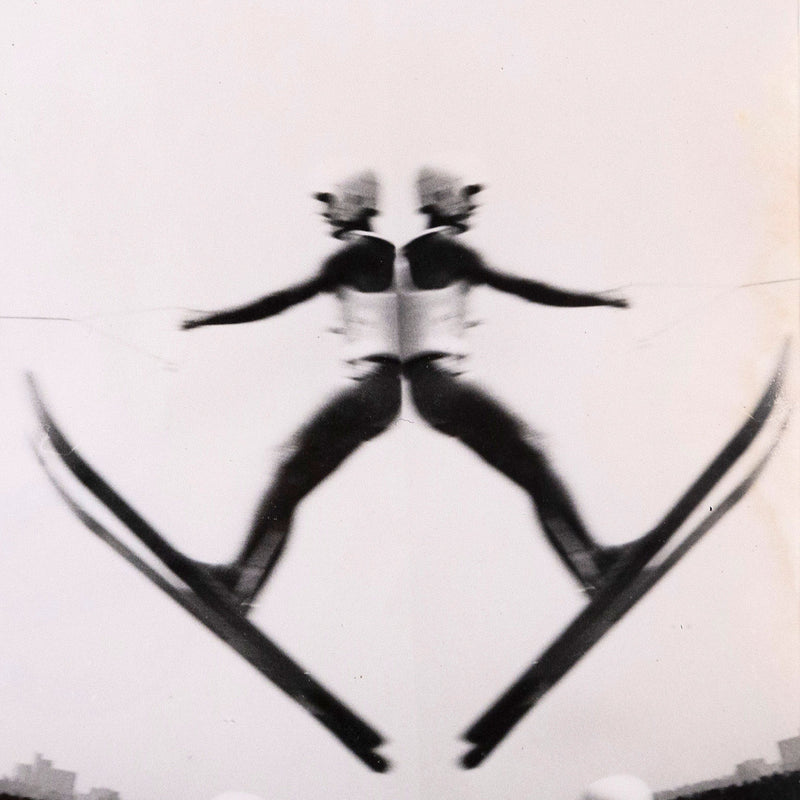 Weegee. Untitled "Waterski Jumper" USA, 1950. Gelatin silver print. Toronto gallery. The dynamic image features two waterskiers, one suspended in the air mid-jump, while the other touches down, prompting a spray of water upon impact. This brief moment of daring motion is distorted into an almost perfectly symmetrical image, with limbs and perspective lines converging at the center for an almost Op Art effect.