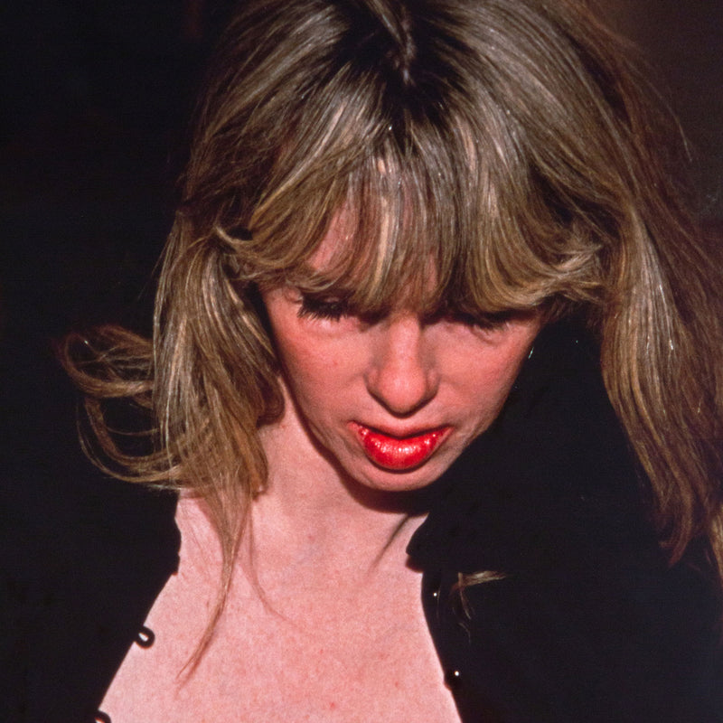 Nan Goldin "Joey with her New Breasts" Dye bleach print, 1999. Joey gently leans into the back of a chair, her chest bare and outwardly exposed. Joey's downward expression is partially hidden by her voluminous fringe, which contributes to her enigmatic presence and continuous glamour. 